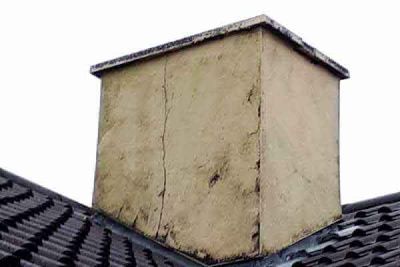 A chimney stack with a crack down the side, on a tiled roof