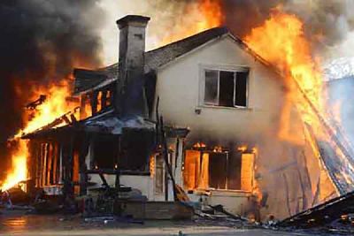 Large flames and black smoke surround a two-storey house