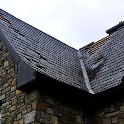 A slate roof on a stone house, with slates missing and timber battens showing