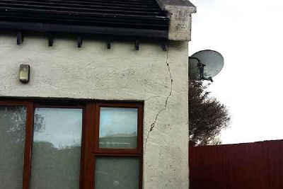 A crack in the wall of a house beside a window