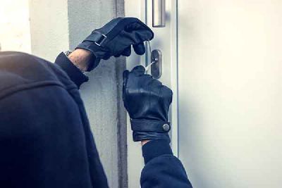 A person in black gloves forces the lock of a door