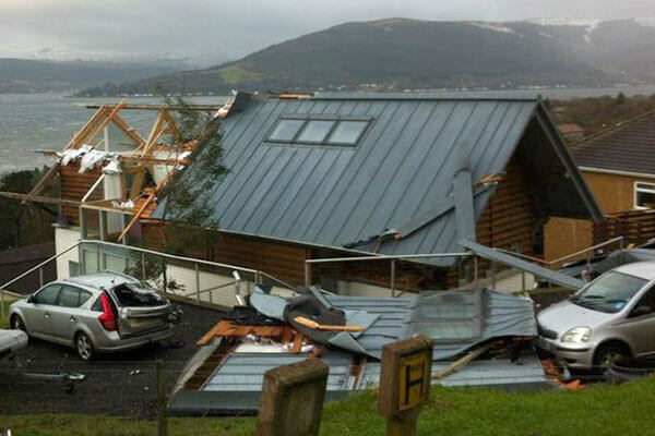 Seaside house with extensive roof damage after a recent storm.